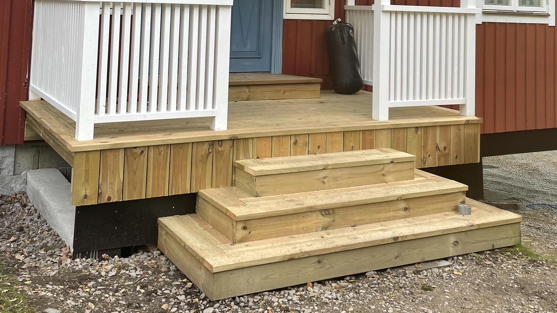 Veranda med trappa vid rött hus